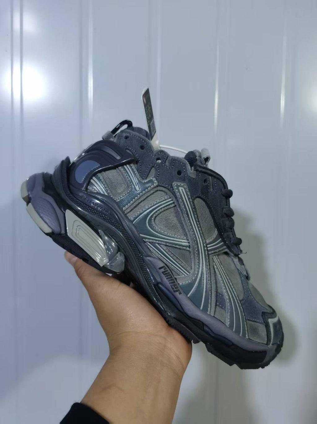 Close angled view of the grey Puma 1100 sneaker showing layered side panels, laces and sculpted sole details.
