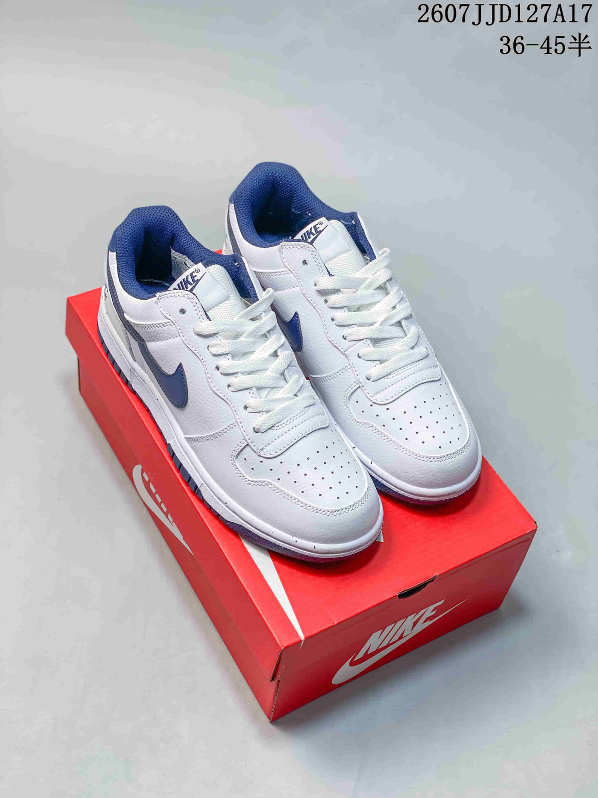 Pair of white and navy Nike SB Dunk Low Pro sneakers displayed on a red shoebox.