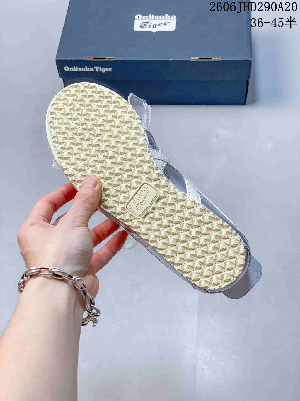 Close-up of the textured cream-colored outsole and side of a silver sneaker.