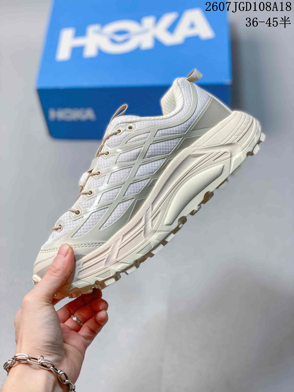 Side view of the white and grey sneaker showing layered upper panels, lace structure and a thick lugged sole.
