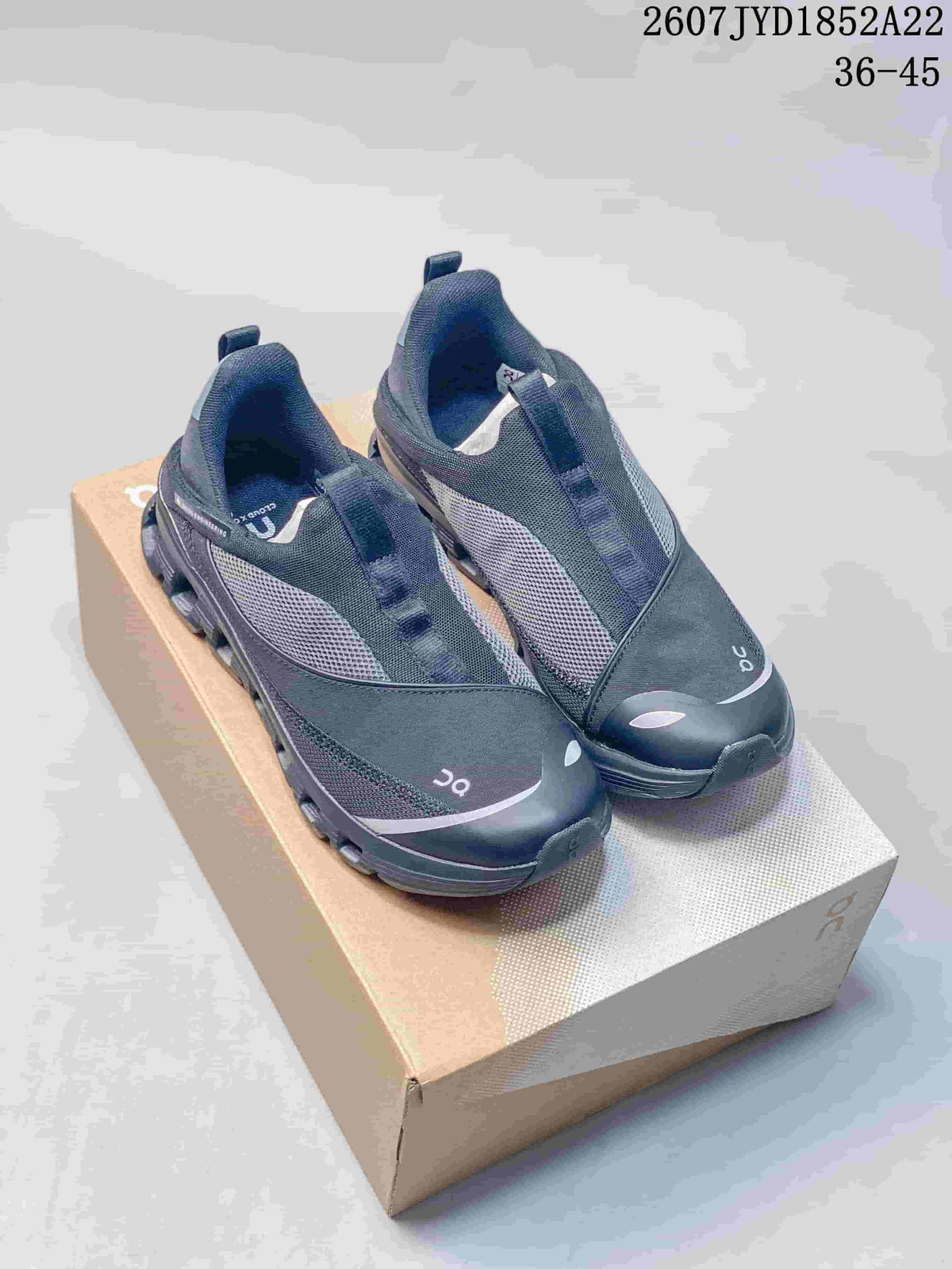 Pair of black On low-top sneakers displayed on a shoe box, showing the mesh upper, layered panels and segmented sole.