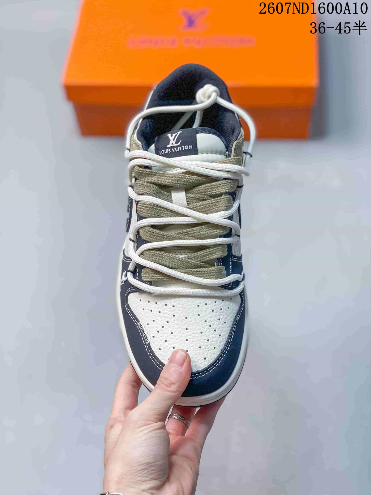 Top view of the sneaker showing the perforated cream toe box, dark overlays, olive tongue area, and multiple light-colored laces.