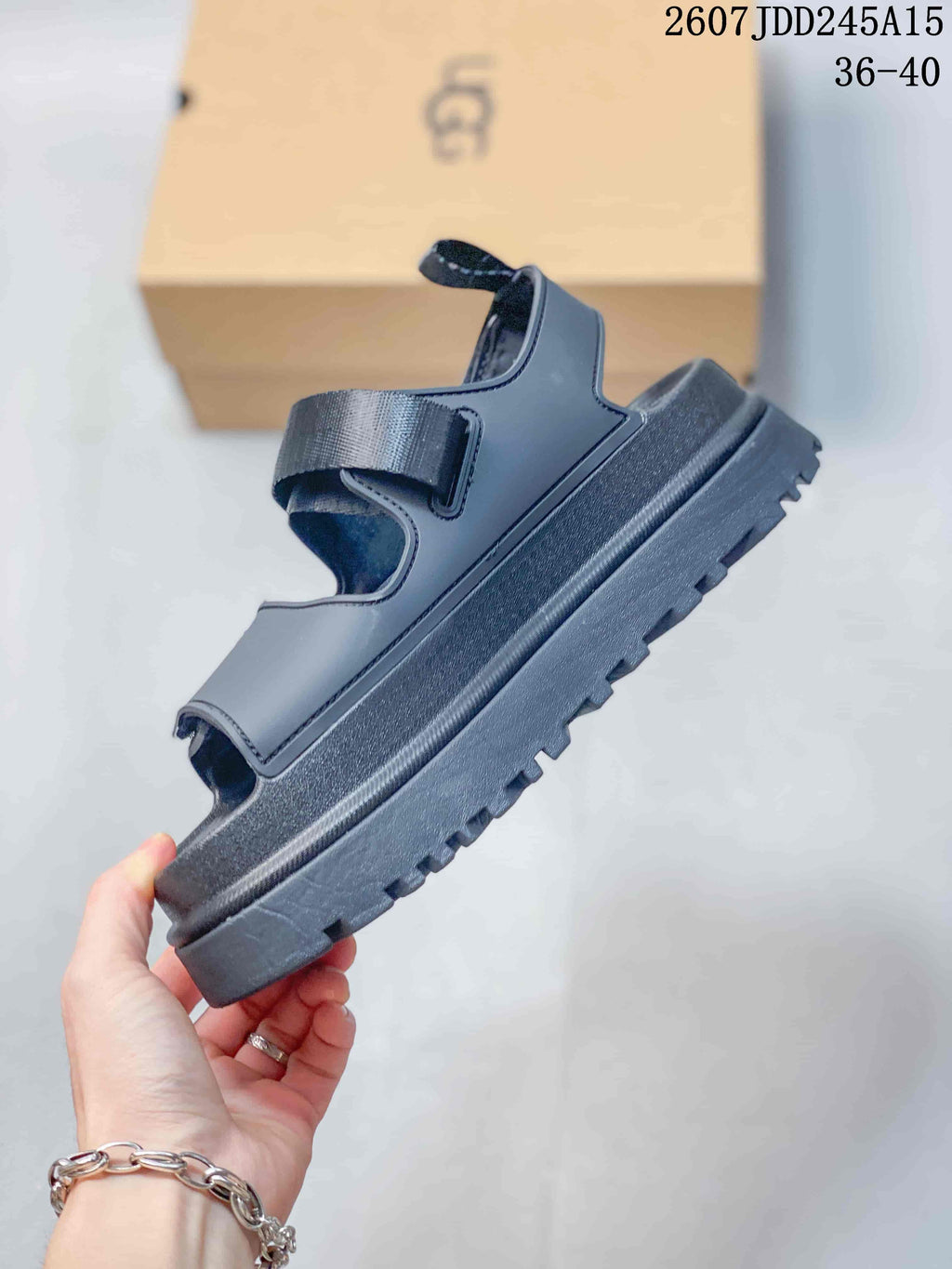 Side view of the black sandal showing its adjustable upper strap, open-toe construction, raised platform sole, and lugged outsole, with product code 2607JDD245A15 and size range 36–40 visible.