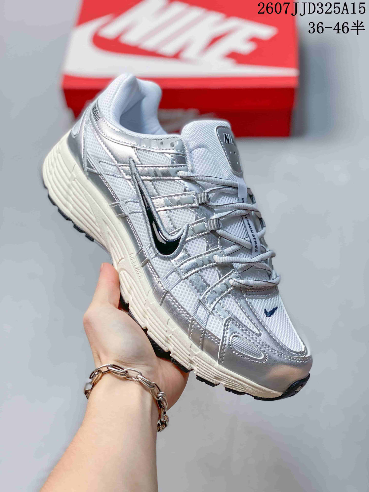 Side and three-quarter view of a white and silver Nike P-6000 sneaker with a dark Swoosh detail and textured sole.