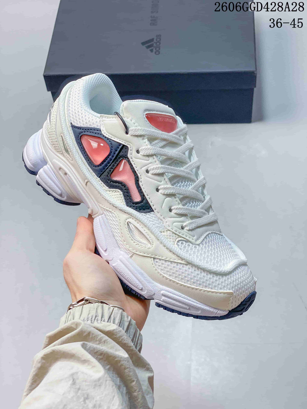 Angled side view of a white low-top sneaker with navy and coral-pink accents