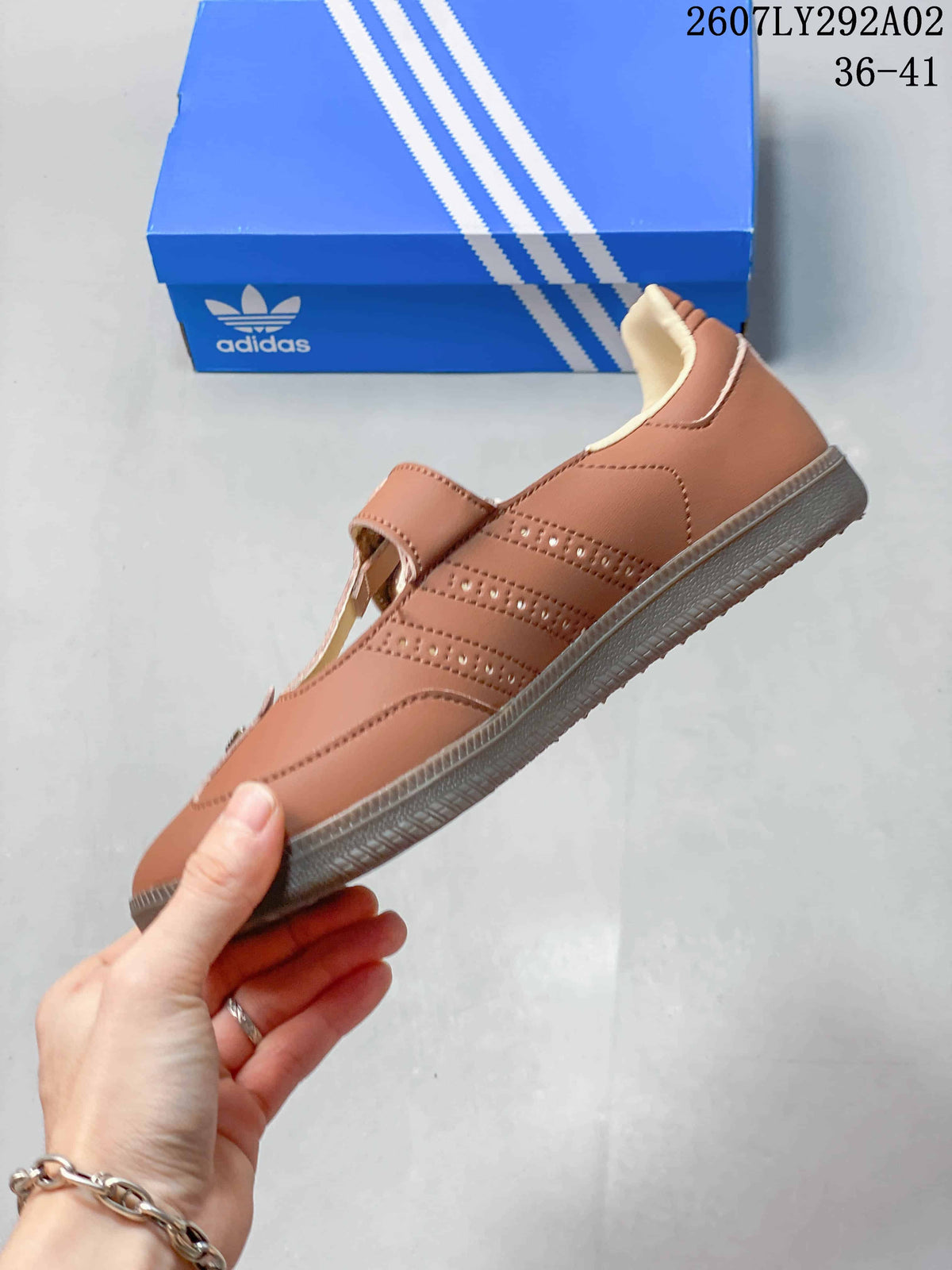 Side view of the brown sneaker showing perforated detailing, stitched panels, cream lining, and the textured outsole.
