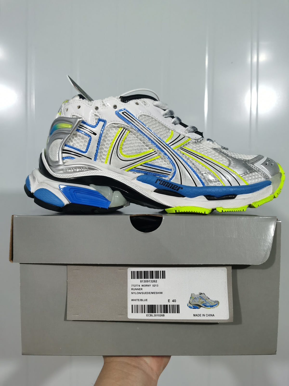 Puma Runner sneaker displayed on its box; the label shows Runner, white/blue color, and size E40.