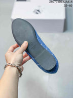 Underside of a blue ballet flat showing the dark outsole, circular logo mark, and a visible size marking.