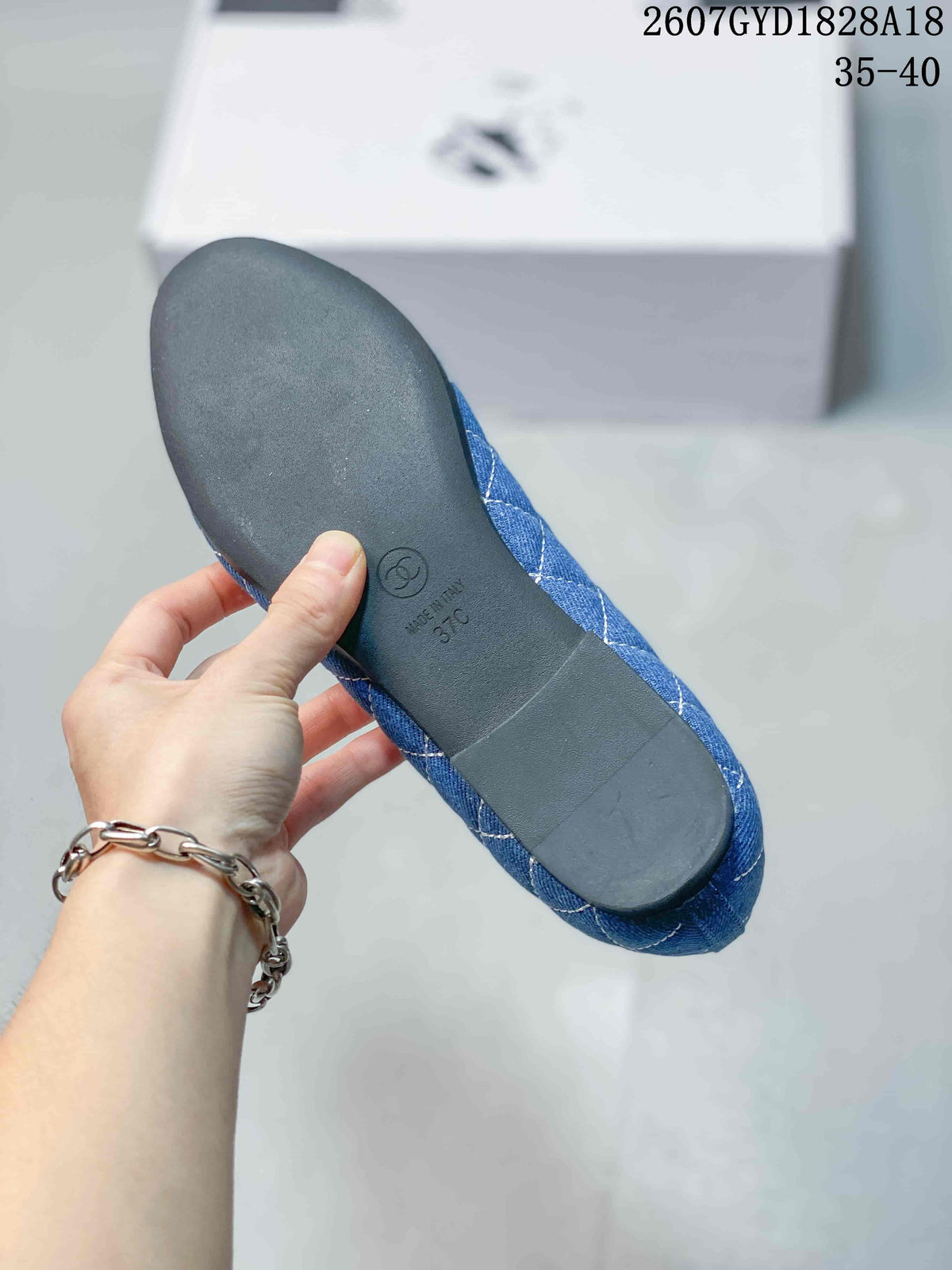 Underside of a blue ballet flat showing the dark outsole, circular logo mark, and a visible size marking.