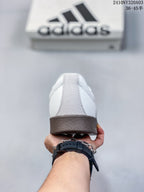 Rear view of a white sneaker showing the gray heel panel and brown textured outsole.