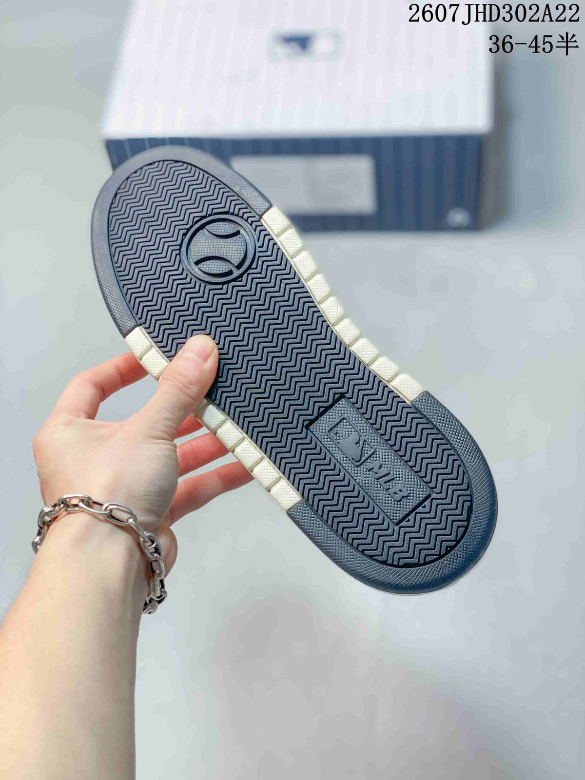 Close-up of the sneaker outsole showing a navy zigzag tread pattern and raised branding details.
