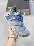 Angled side view of the blue The North Face sandal showing the open design, webbing straps and branded side panel.