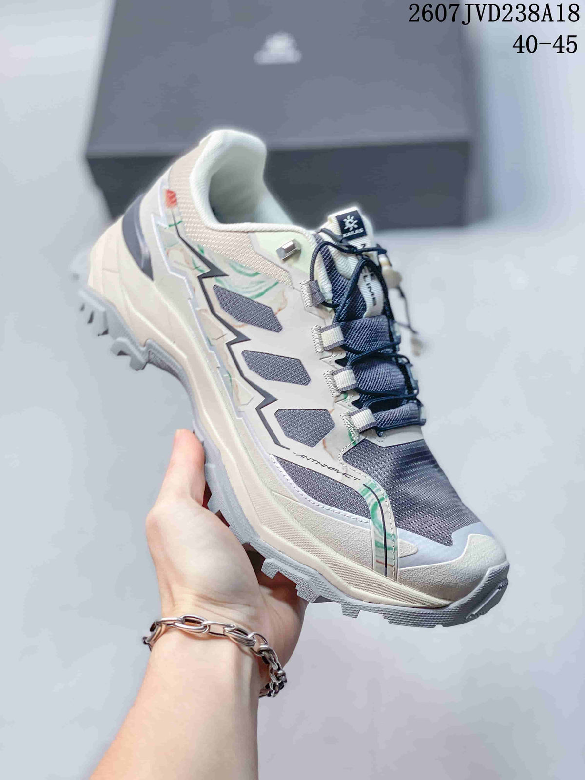 Close side view of the light gray KAILAS hiking shoe with dark laces, green accent details, layered panels, and rugged outsole.