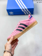 Side profile of the pink sneaker showing black three-stripe detailing and the low-top silhouette.