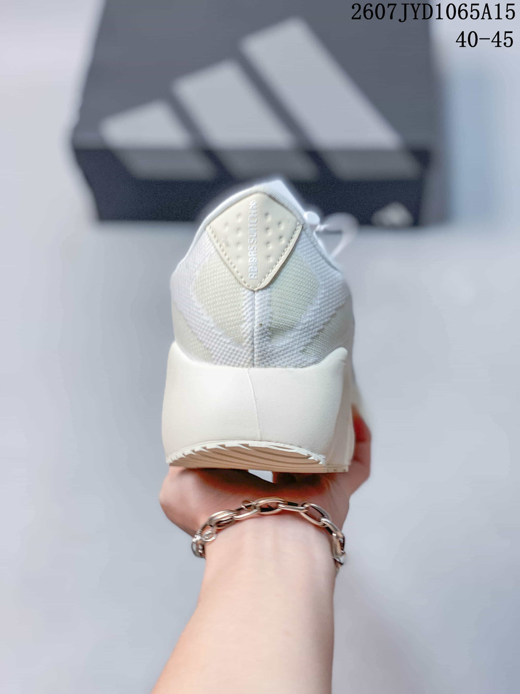 Rear view of the white sneaker showing the padded heel, textile upper, and heel label with visible branding.