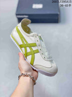 Angled side view of the white and green low-top sneaker with its lace-free front design.