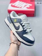 Navy and white Nike SB Dunk Low Pro sneaker with a sun-style side detail, photographed against a red shoebox.
