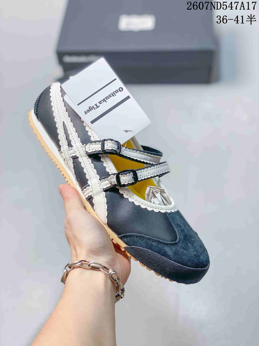 Dark Mary Jane sneaker with contrasting white side stripes, two straps and a tan-colored outsole.