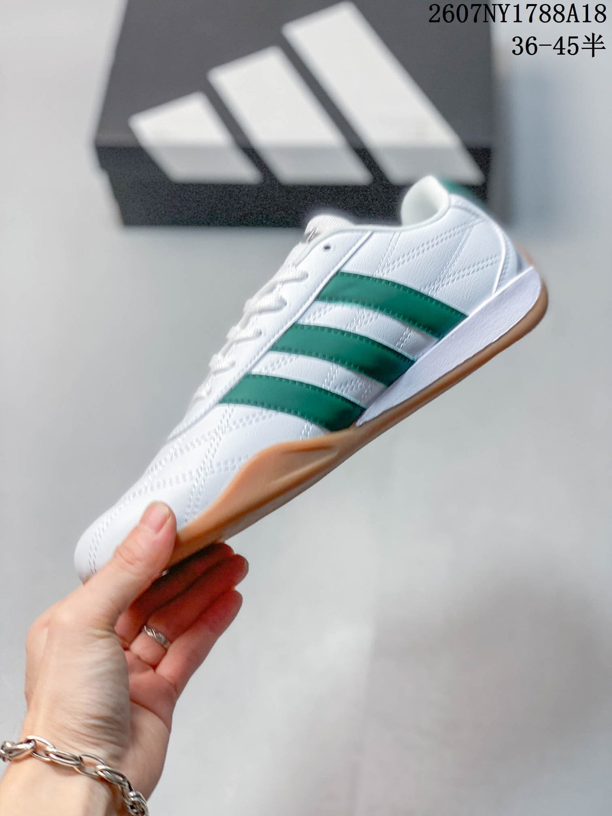 Side view of the white adidas Adipista trainer with green stripes and a gum-colored sole
