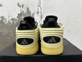 Rear view of cream, black and yellow basketball sneakers with three-stripe heel panels