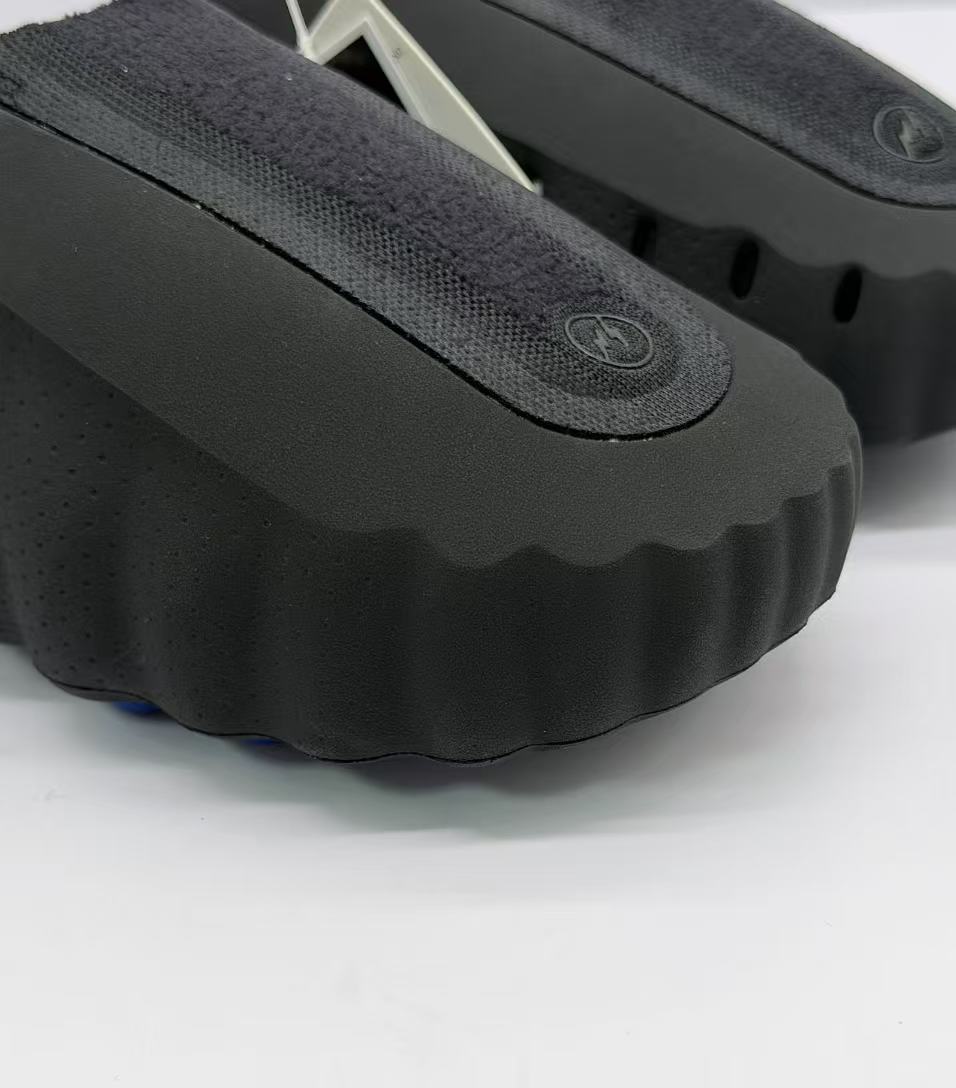 Close-up of the textured black upper, circular emblem and scalloped front edge.