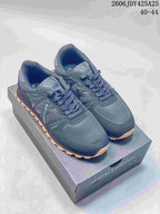 Pair of navy AX sneakers with gum-tone outsoles shown on a branded box.