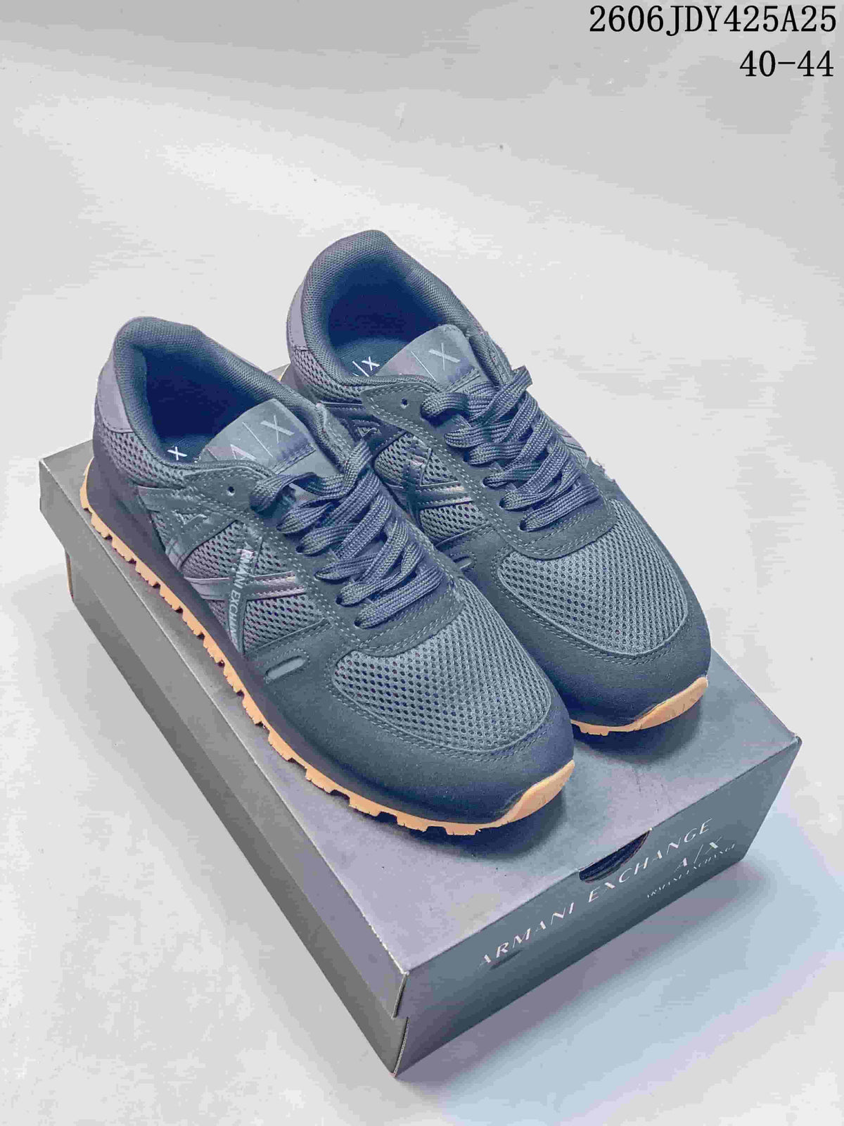 Pair of navy AX sneakers with gum-tone outsoles shown on a branded box.