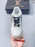 Top view of the white sneaker showing the perforated toe box, dark blue laces, and metal lace accessory.