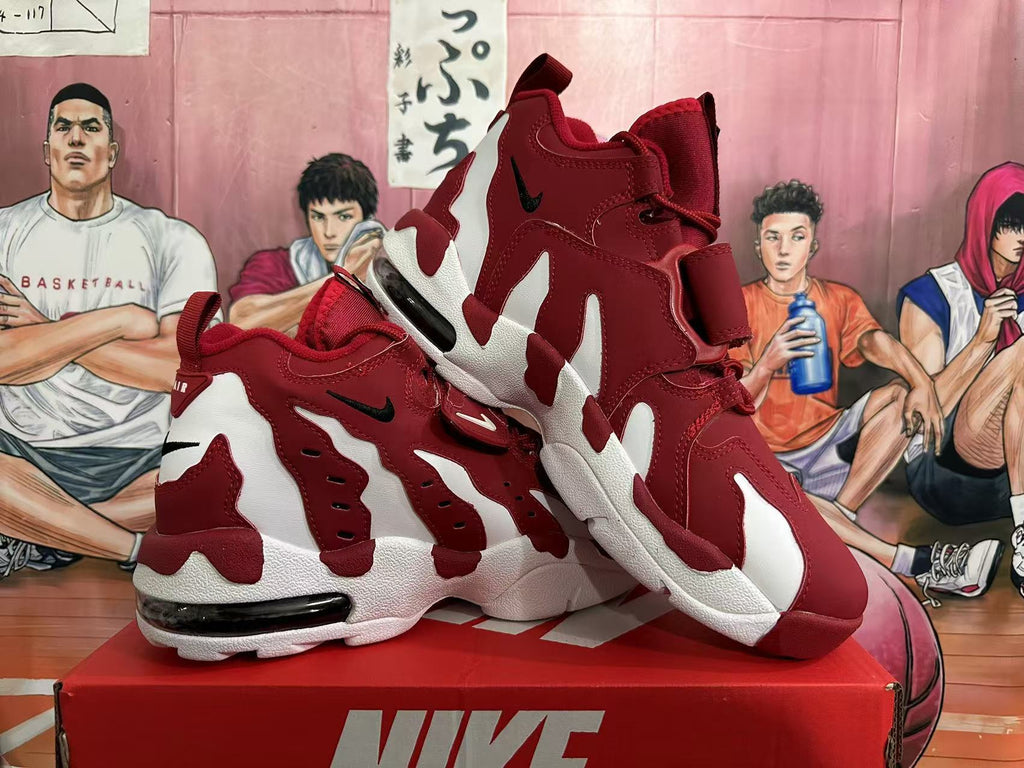 Angled view of red and white Nike sneakers displayed together, showing the high-top shape, layered panels, straps, and contrasting soles.