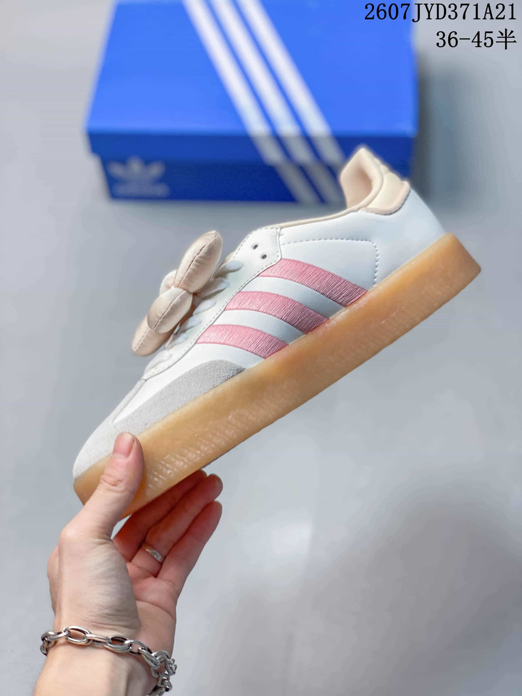 Side profile showing the white upper, three pink stripes, flower detail, and gum-colored outsole.