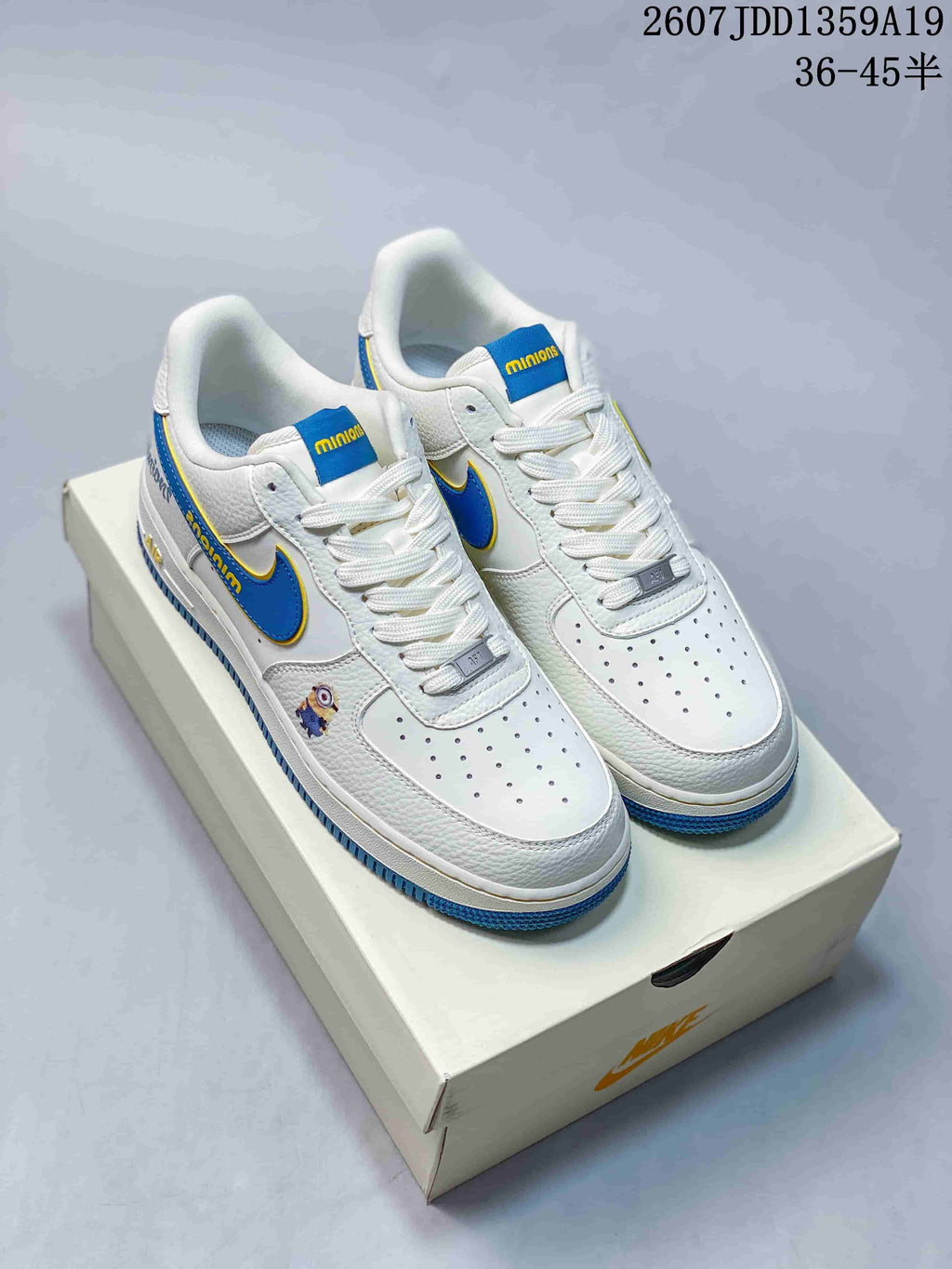 Pair of white Nike Air Force 1 low-top sneakers with blue and yellow Minions details, shown on a shoe box.