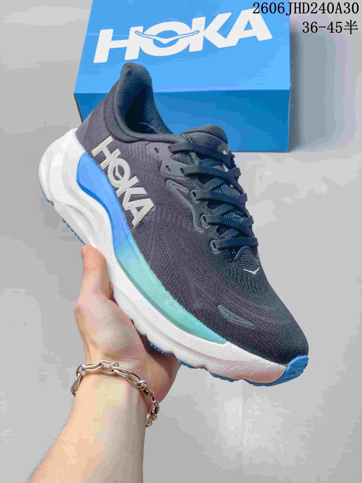 Angled side view of a charcoal HOKA running shoe with a white midsole and blue and aqua details.
