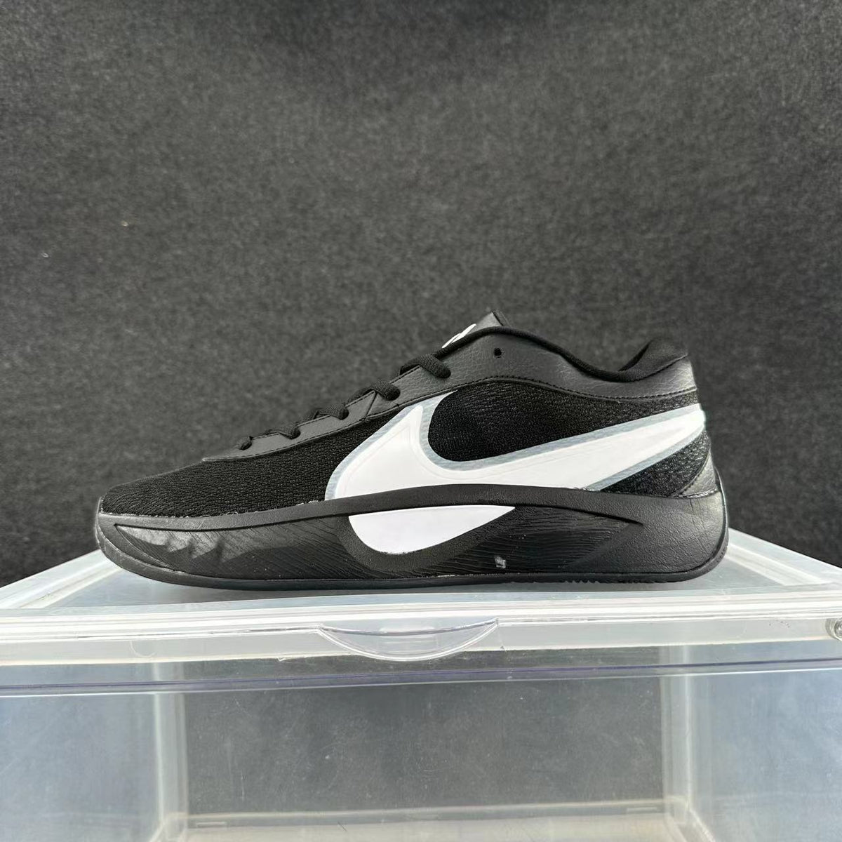 Side view of a black low-top Nike sneaker with white side detailing and a dark sculpted sole.