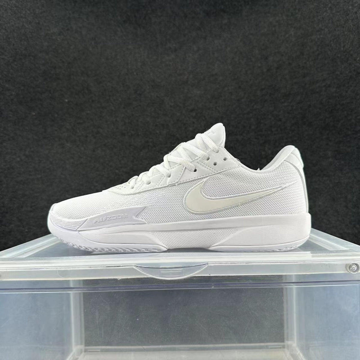 White low-top Nike sneakers with a mesh-like upper, lace-up closure, and Zoom marking, shown from the side.