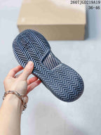 View of the black tennis shoe outsole showing its zigzag tread pattern, with a box behind it.