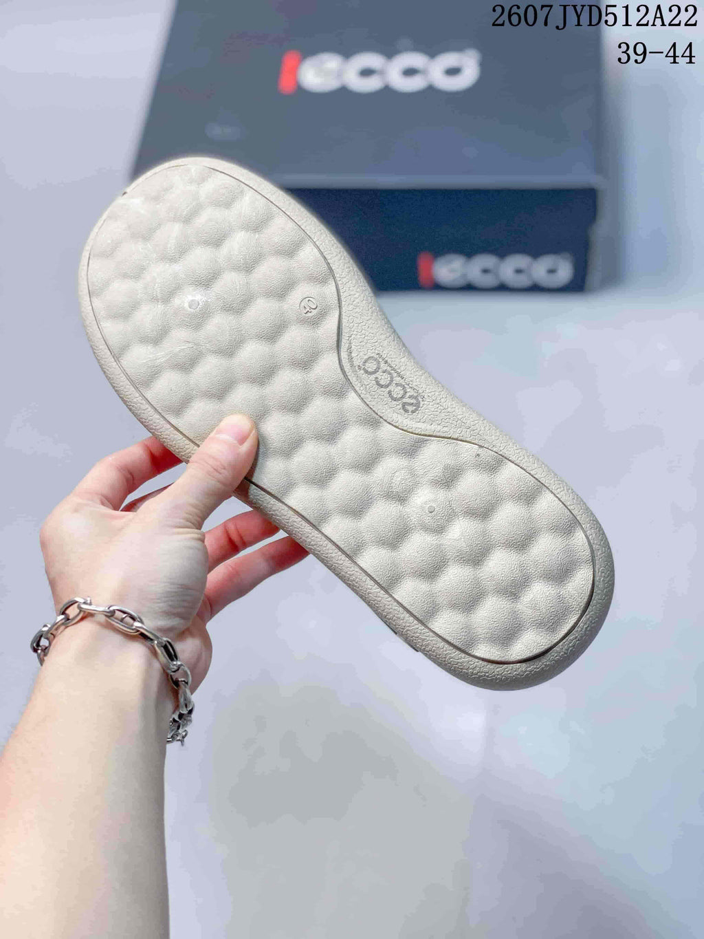 Close view of the textured light-colored outsole of a gray ECCO sneaker, with ECCO branding visible.