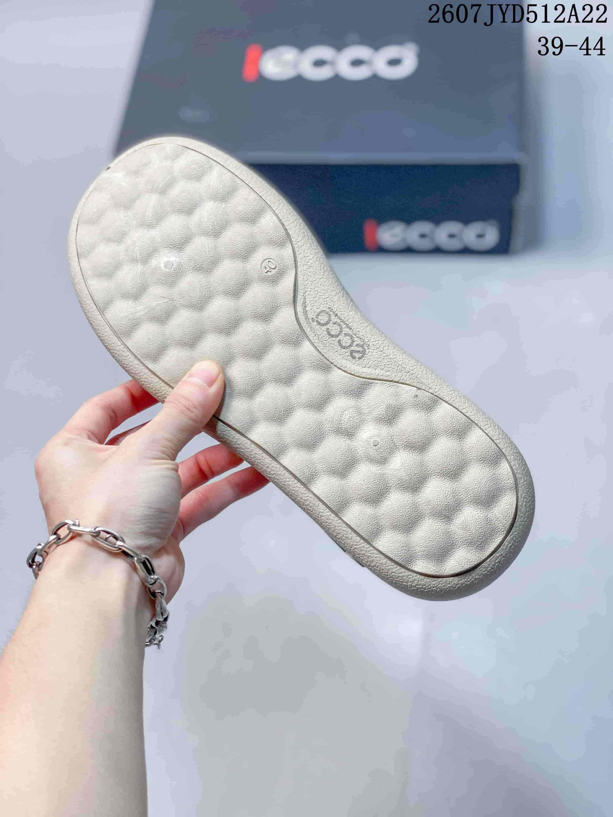 Close view of the textured light-colored outsole of a gray ECCO sneaker, with ECCO branding visible.