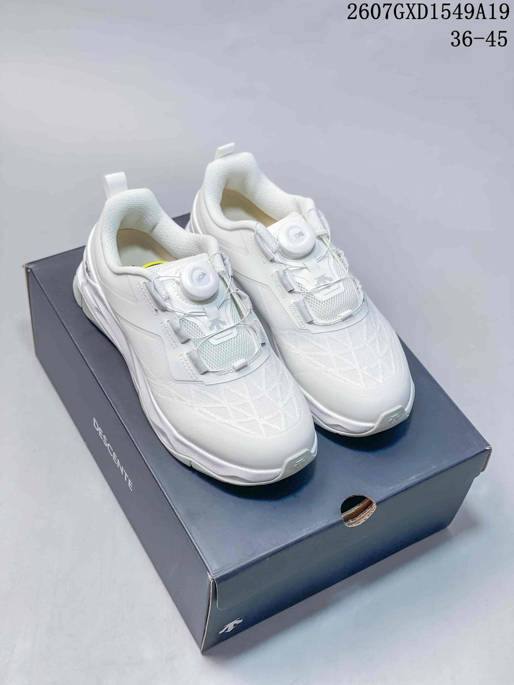White DESCENTE Circuit 2.0 Wire sneakers displayed on a branded shoebox, with the source code and size range visible above.