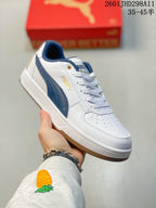 Close-up side view of a white and navy Puma Caven 2.0 sneaker showing the side stripe, perforated toe, and flat outsole.