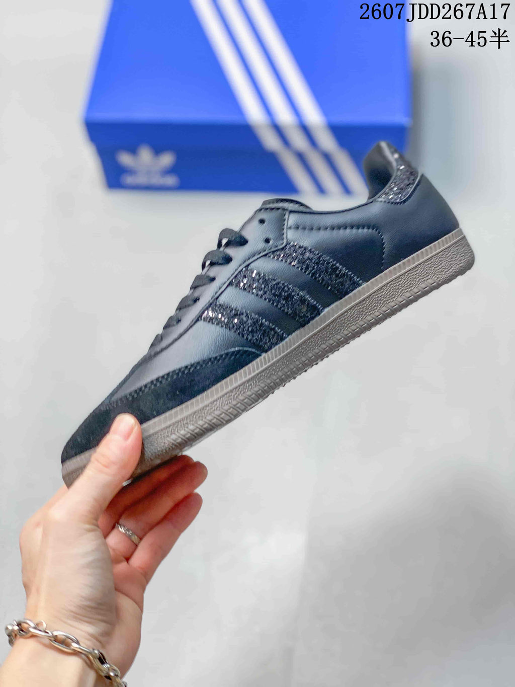 Side profile of the black low-top sneaker showing the glitter-style three-stripe detail and gum-colored outsole.