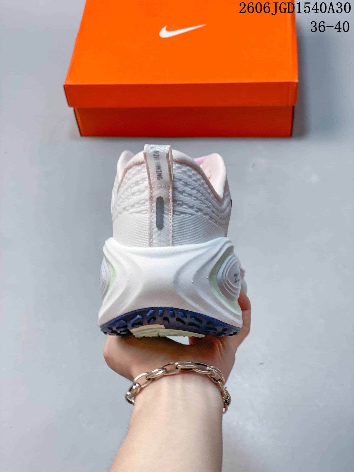 Rear view of a white Nike Vomero Plus shoe with a sculpted heel and dark outsole.