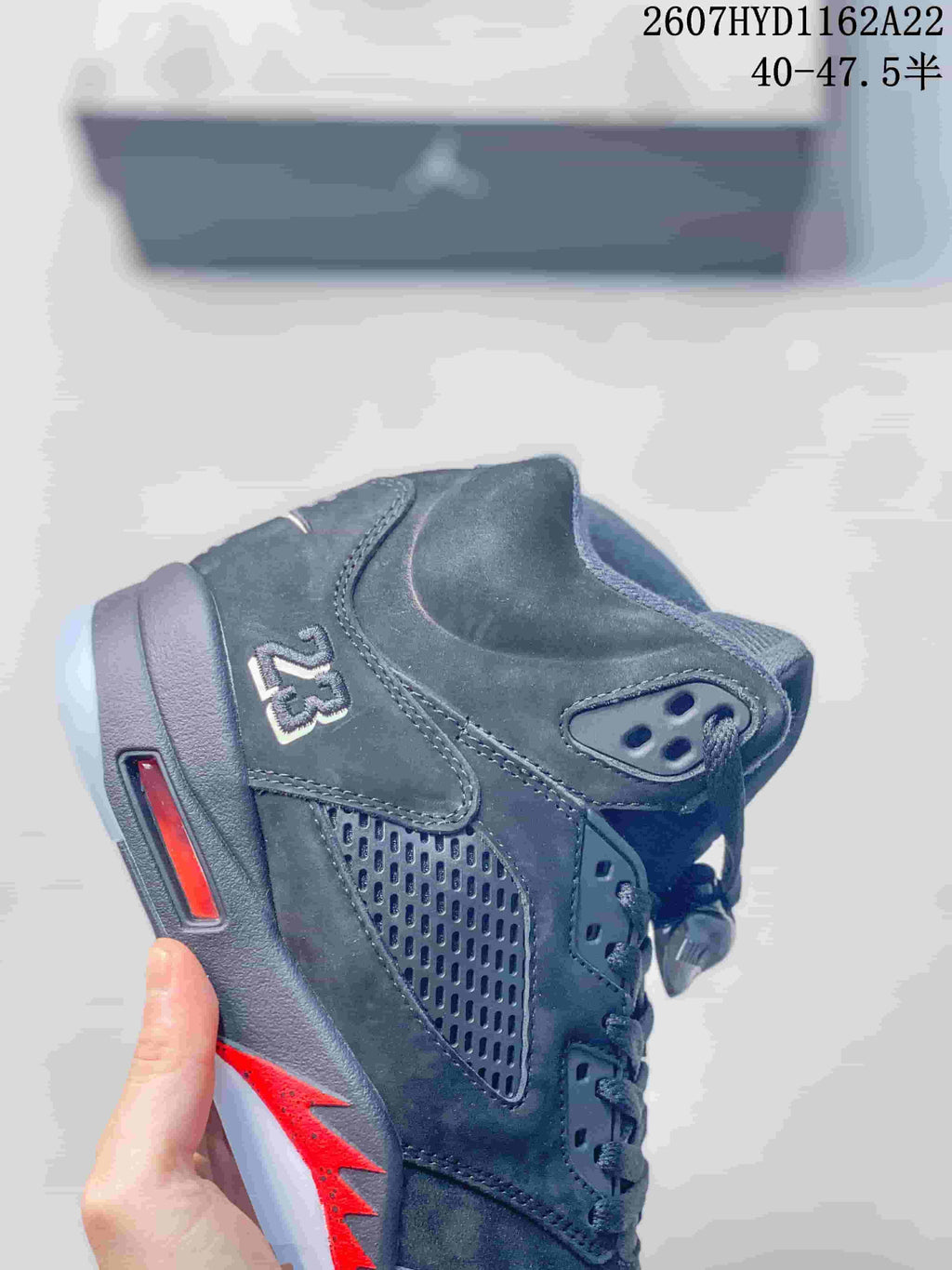 Close-up of a black high-top sneaker showing the Jordan 5 side panel, perforations, red midsole accent and heel detail.