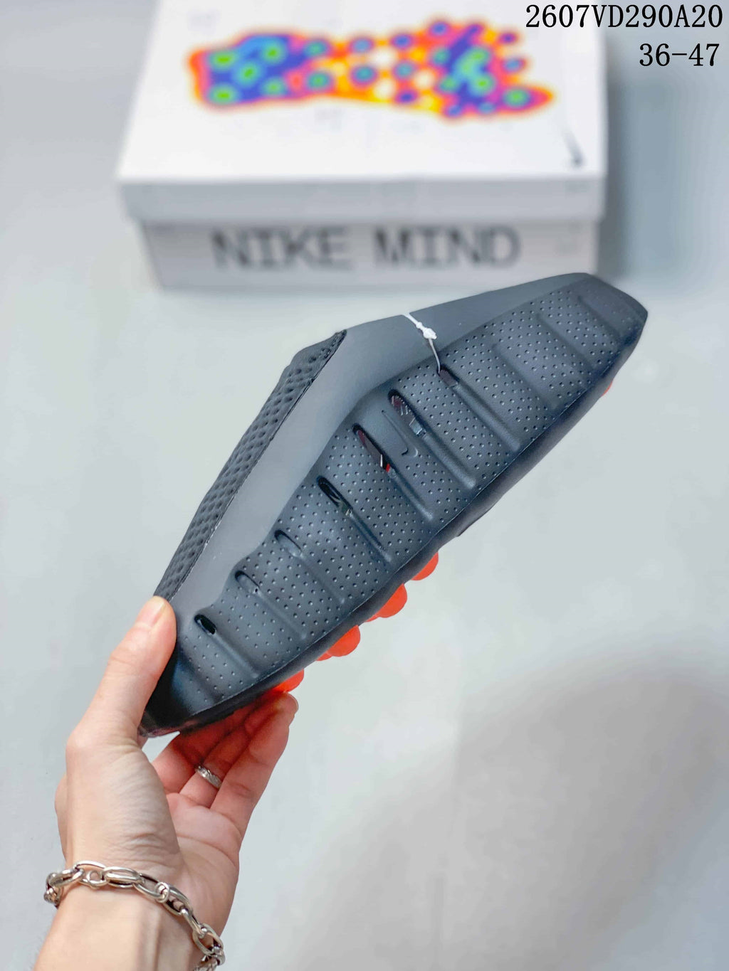 Side view of the slide showing perforated panels, a sculpted sole edge, and orange outsole pods.