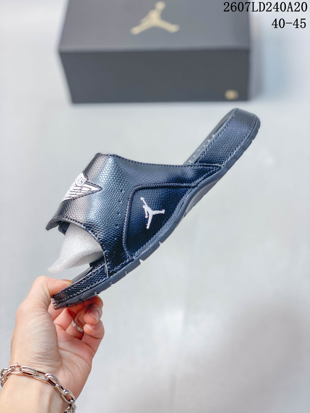 Side view of a dark Jordan slide showing the adjustable strap, open toe, and Jordan side branding; style code 2607LD240A20 and size range 40–45 appear above.