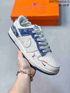 Angled side view showing the white and blue upper, monogram-style side graphics, patterned heel area, and blue outsole.