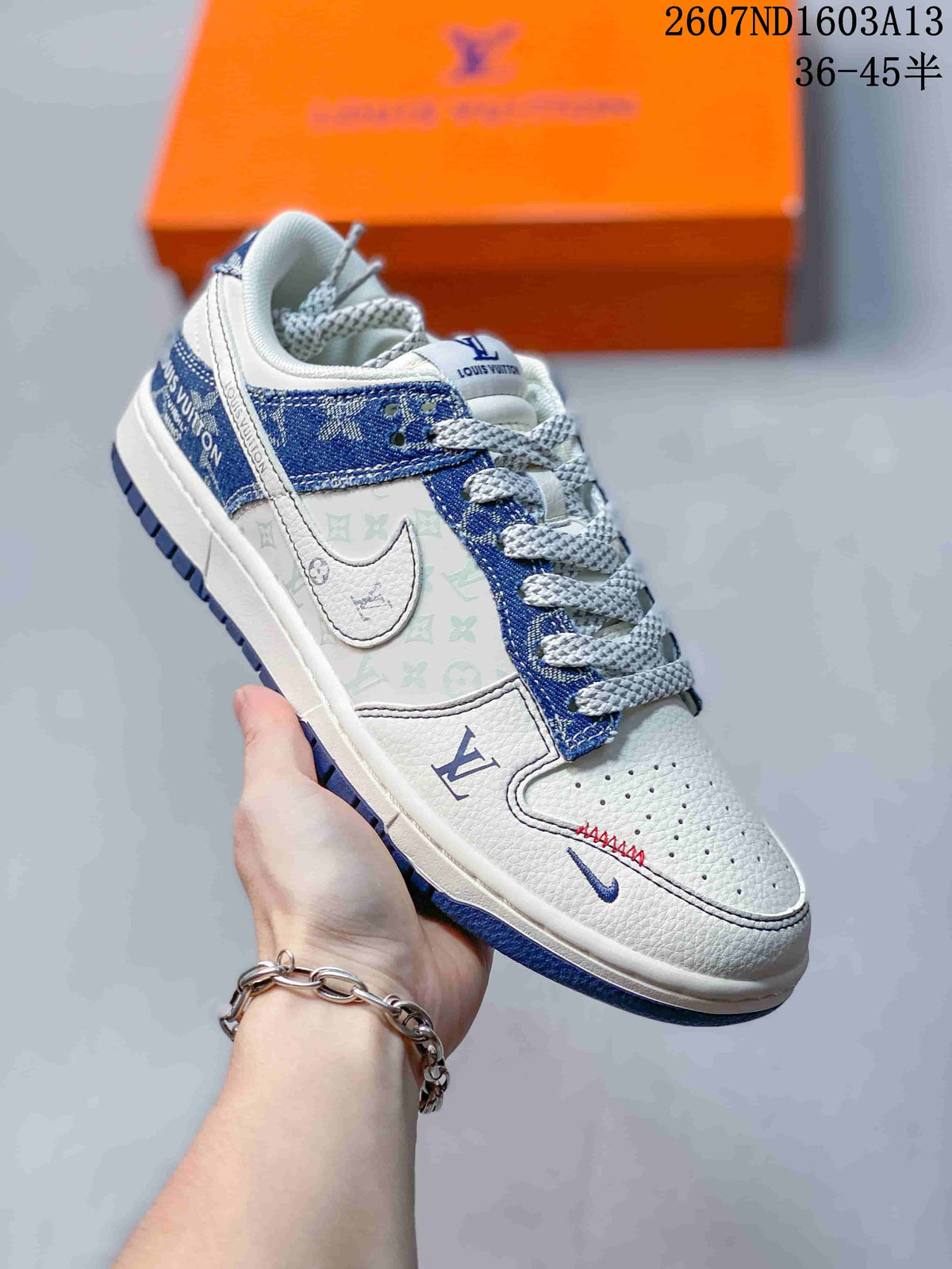 Angled side view showing the white and blue upper, monogram-style side graphics, patterned heel area, and blue outsole.