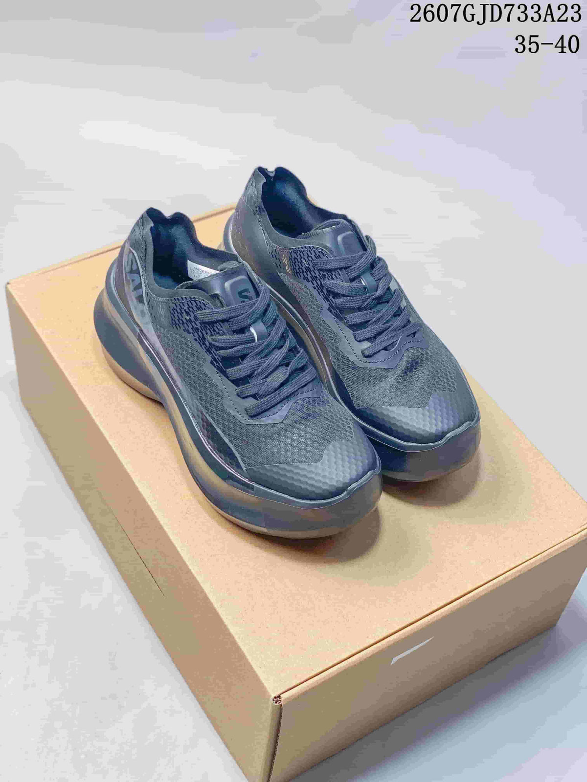 Pair of dark gray and black Salomon low-top sneakers displayed on a cardboard box.