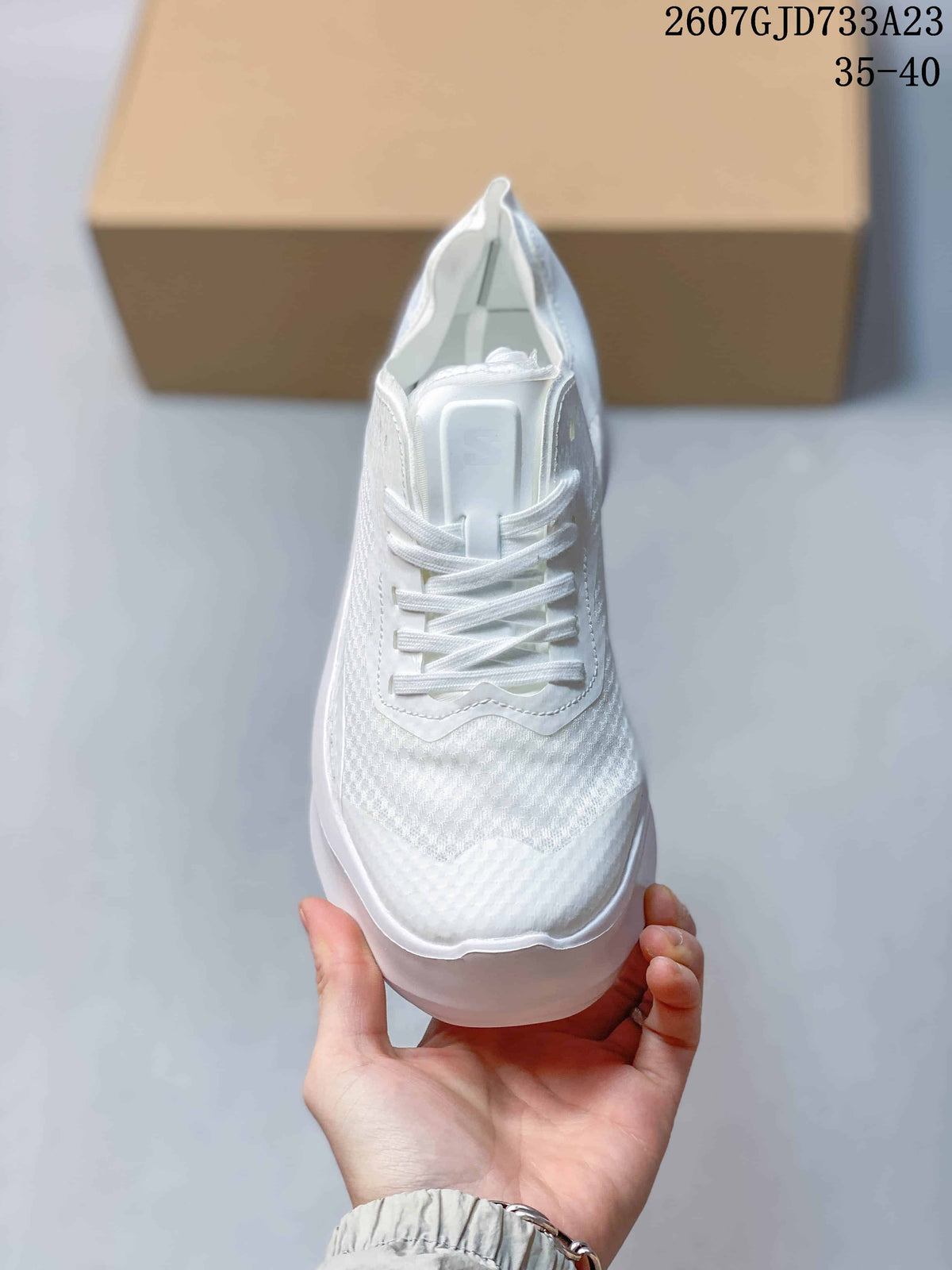 Top view of the white sneaker showing the lace-up front, tongue, textured toe area, and tonal detailing.