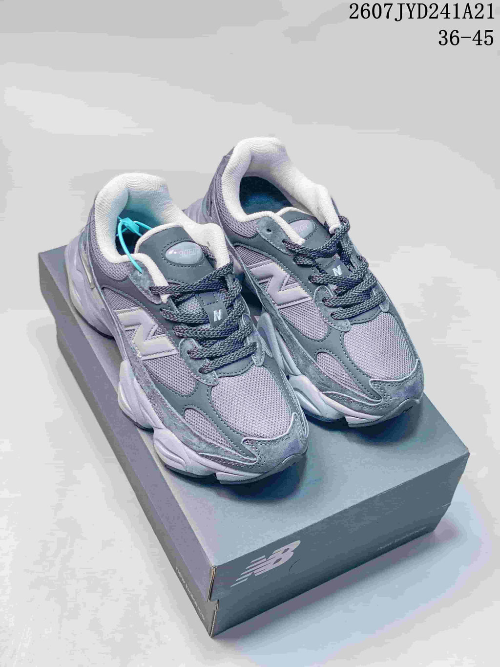 Pair of gray New Balance 9060 sneakers displayed on a branded shoebox.