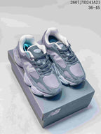 Pair of gray New Balance 9060 sneakers displayed on a branded shoebox.